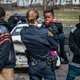 Officer Bridget Balasko holds a small child while her father is being searched and questioned.